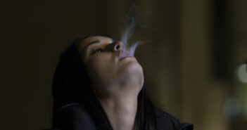 woman standing while blowing smoke