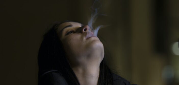 woman standing while blowing smoke