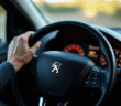 Main du conducteur sur le volant Peugeot 2008 avec voyant allumé
