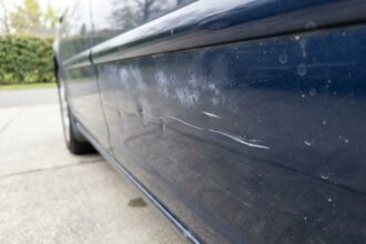 Gros plan sur des rayures et bosses sur la carrosserie d'une voiture bleue avant revente
